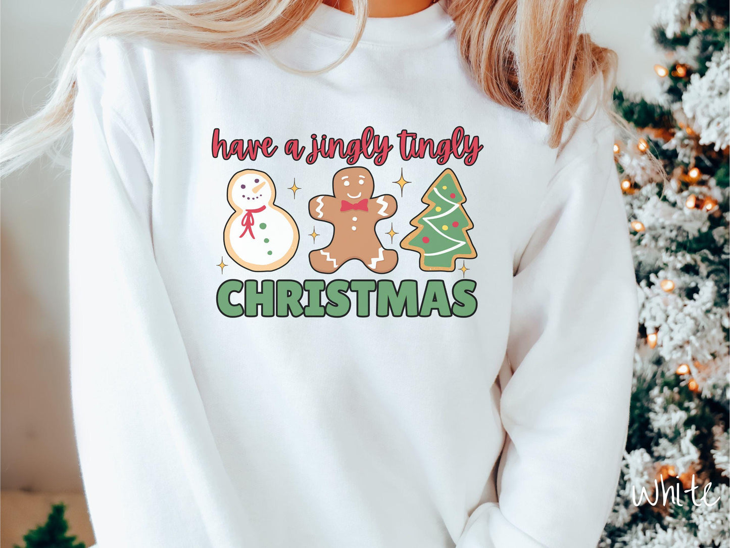 A vintage white colored Christmas Gildan sweatshirt featuring a snowman iced cookie, a gingerbread man cookie, and a Christmas tree cookie. The text reads 'have a jingly tingly Christmas' in red and green font.