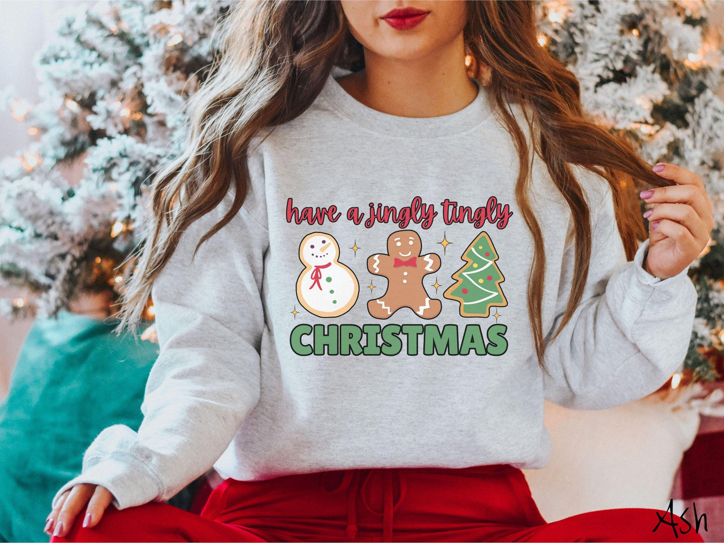 A vintage ash colored Christmas Gildan sweatshirt featuring a snowman iced cookie, a gingerbread man cookie, and a Christmas tree cookie. The text reads 'have a jingly tingly Christmas' in red and green font.