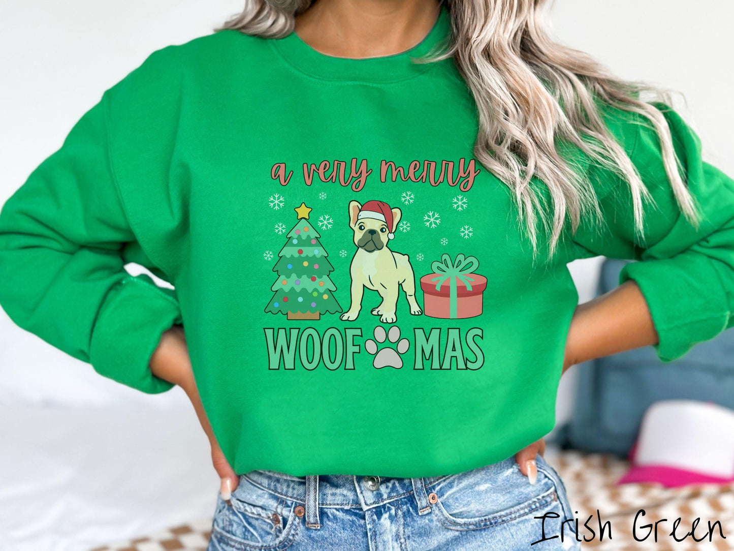 A vintage Irish green colored Gildan sweatshirt with text 'a very merry Woofmas' in red and green font, featuring a French Bulldog wearing a red Santa hat sitting between a Christmas tree and a present with white snowflakes hanging in the air.