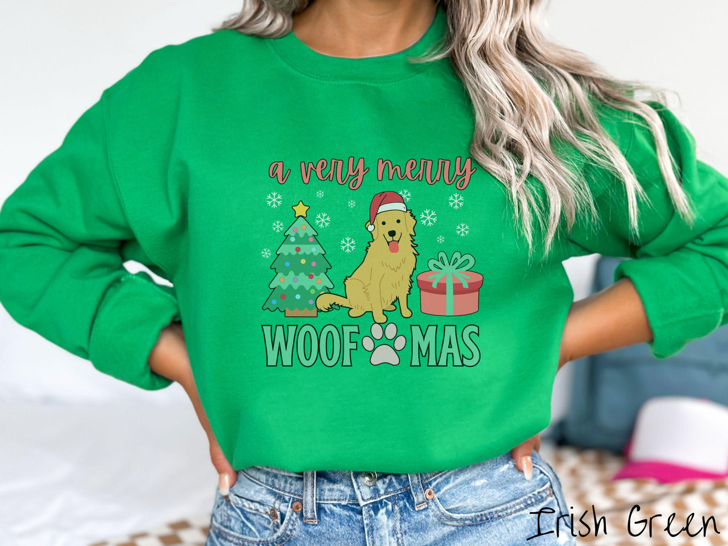 A vintage Irish green colored Gildan sweatshirt with the text 'a very merry Woofmas' in red and green font, featuring a Golden Retriever wearing a red Santa hat sitting between a Christmas tree and a present with white snowflakes hanging in the air.