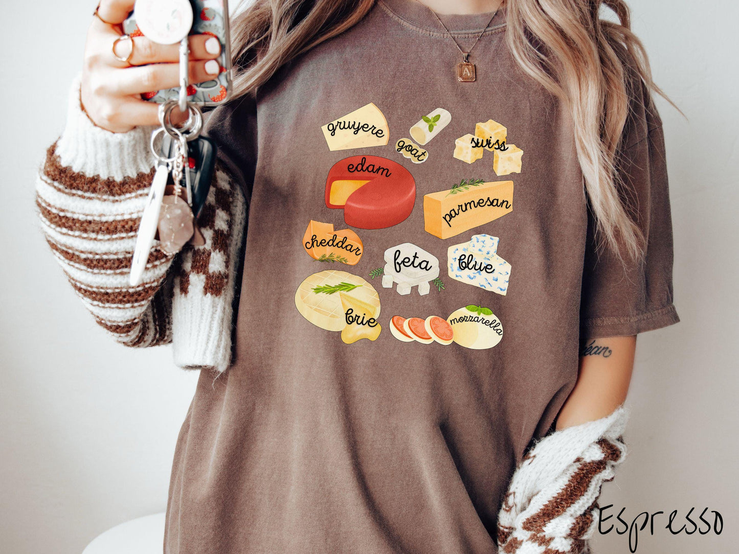 A vintage espresso colored T-shirt is perfect for cheese lovers with a grid pattern of various cheeses like feta, parmesan, gruyere, goat, swiss, edam, cheddar, blue, brie, and mozzarella listed.