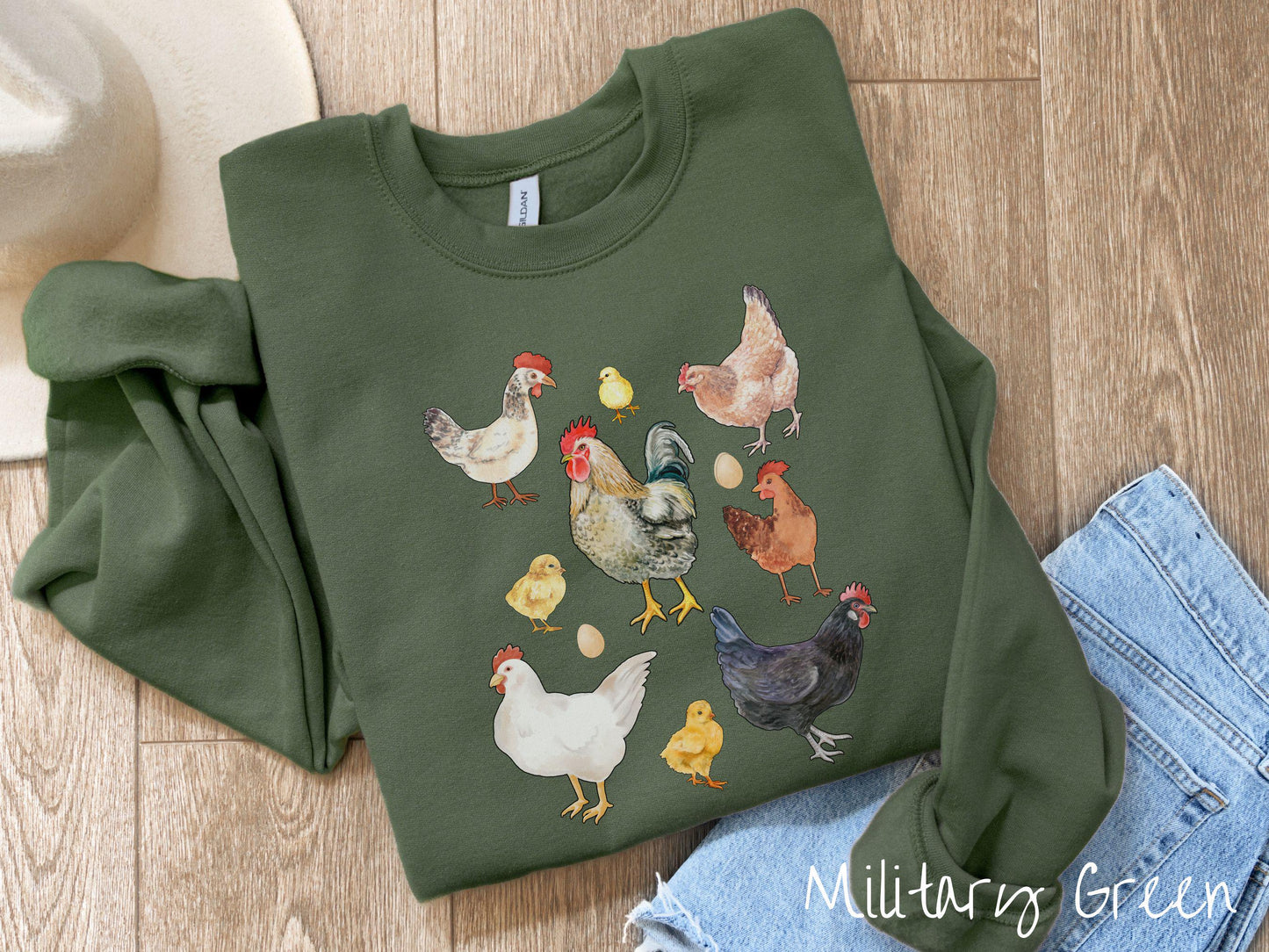A vintage military green colored Gildan sweatshirt featuring a grid style design of assorted colorful chickens, hens, and roosters in a grid design, with chicken eggs scattered among the design.