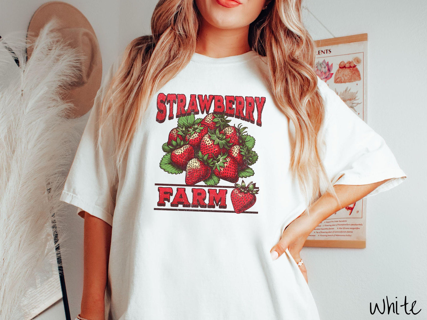 A vintage white colored Comfort Colors t-shirt featuring the text Strawberry Farm in red font with a bundle of red strawberries in between the text.