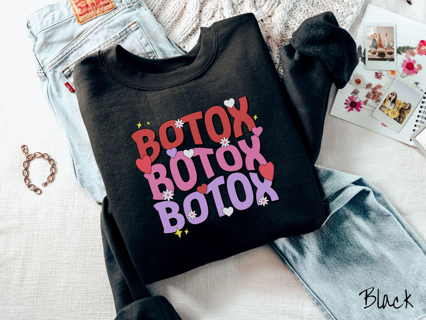 A vibrant Gildan sweatshirt with the text BOTOX written three times vertically, accompanied by tiny hearts, stars, and flowers. The perfect gift for friends who are into cosmetic botox nursing.