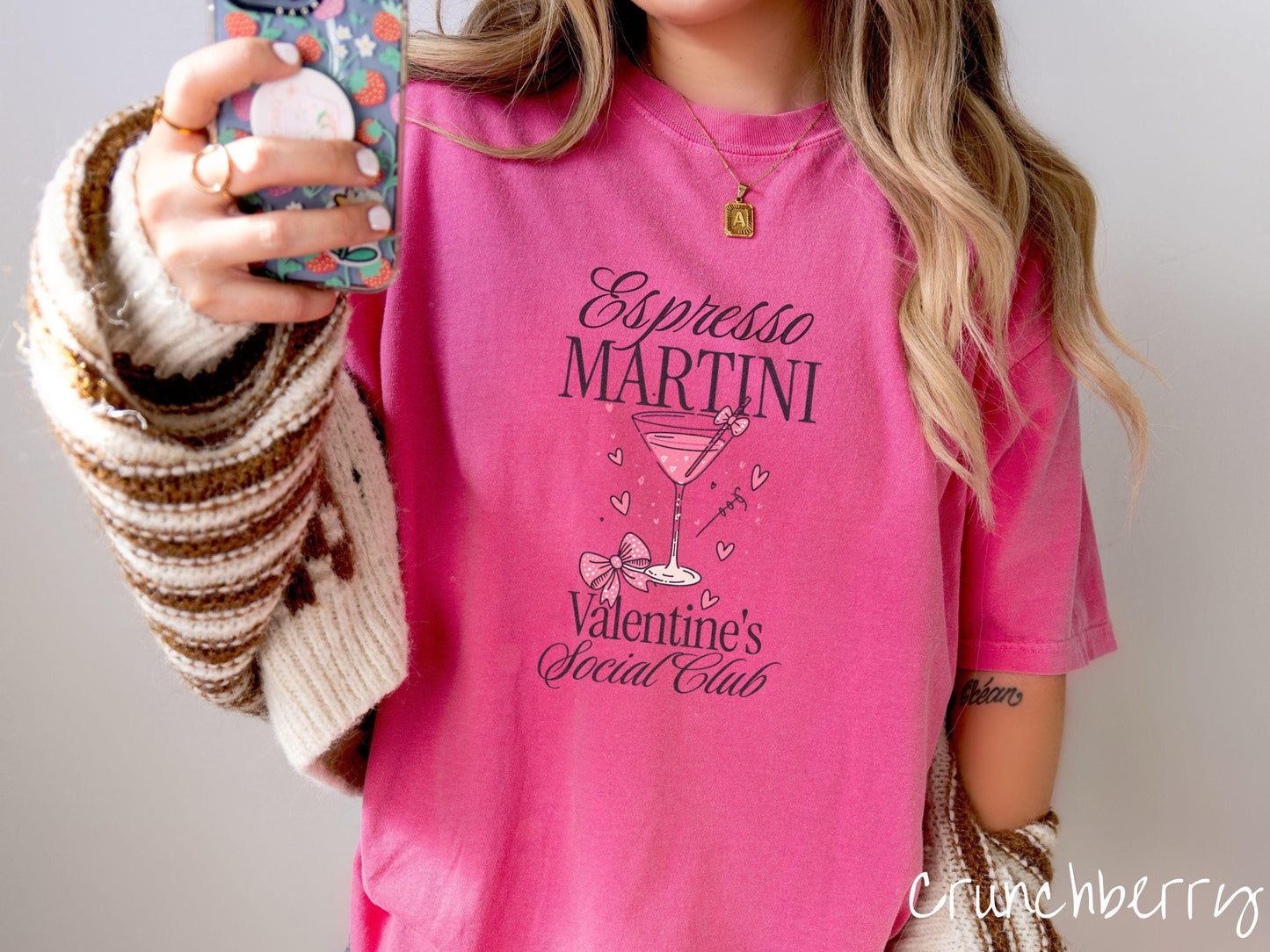 A stylish Comfort Colors T-shirt featuring the phrase "Espresso Martini" above a martini glass filled with pink martini a pink bow-topped toothpick. The words "Valentine's Social Club" appear below, with pink bows and hearts throughout the design.