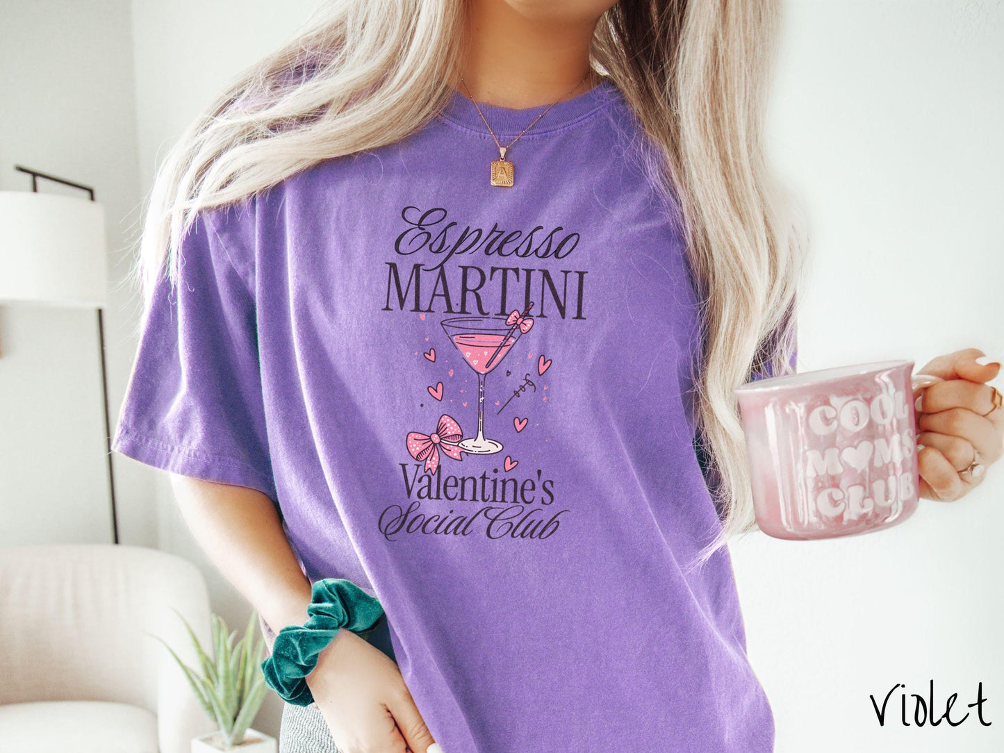 A stylish Comfort Colors T-shirt featuring the phrase "Espresso Martini" above a martini glass filled with pink martini a pink bow-topped toothpick. The words "Valentine's Social Club" appear below, with pink bows and hearts throughout the design.