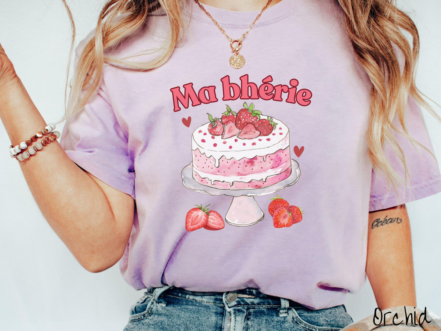 A Comfort Colors T-shirt featuring the phrase "Ma Bherie" is printed in bold red font above a charming illustration of a red-and-white strawberry cake displayed on a plate, topped with fresh strawberries and surrounded by even more berries.