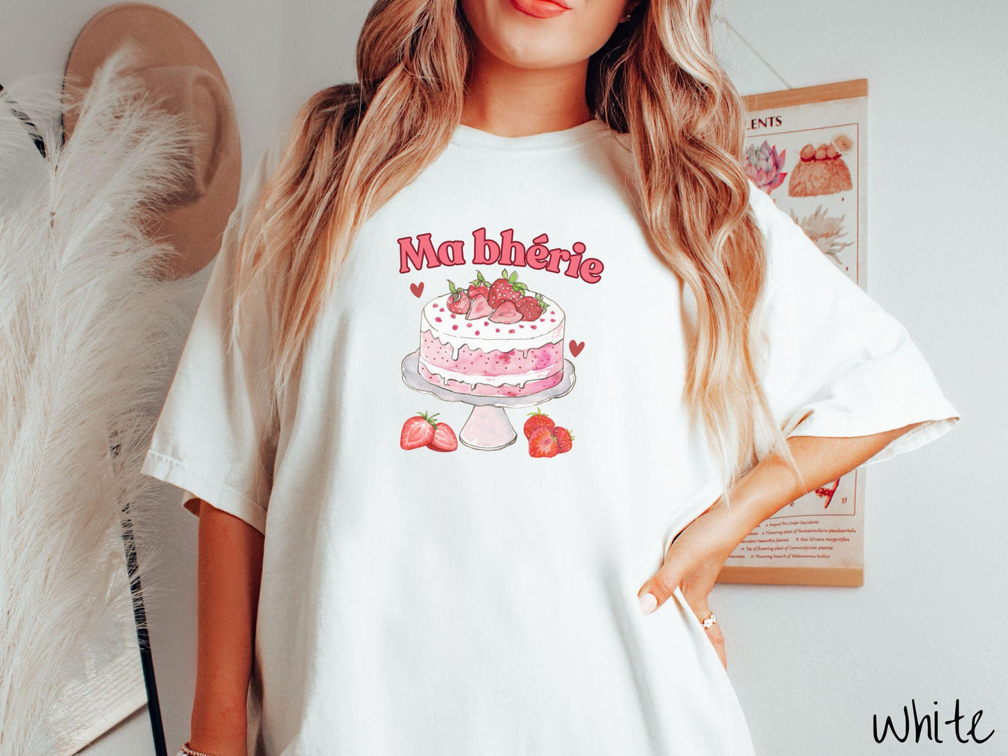A Comfort Colors T-shirt featuring the phrase "Ma Bherie" is printed in bold red font above a charming illustration of a red-and-white strawberry cake displayed on a plate, topped with fresh strawberries and surrounded by even more berries.