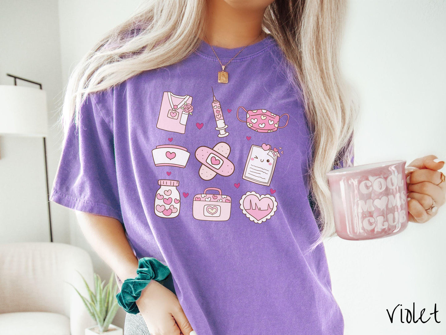 A Comfort Colors T-shirt featuring a 3x3 grid of nursing-themed illustrations adorned with heart designs like nursing scrubs, syringes, a face mask, a nurse cap, bandages, medical records, vitamins, a medical bag, and a heart-shaped EKG graph.