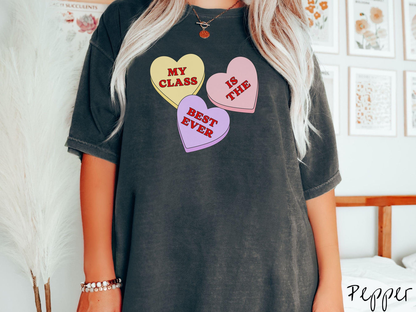 A charming vintage-style Valentine’s Day Comfort Colors t-shirt featuring three vibrant conversation hearts in yellow, red, and purple, this design displays the text “My class is the best ever” spread across the hearts.