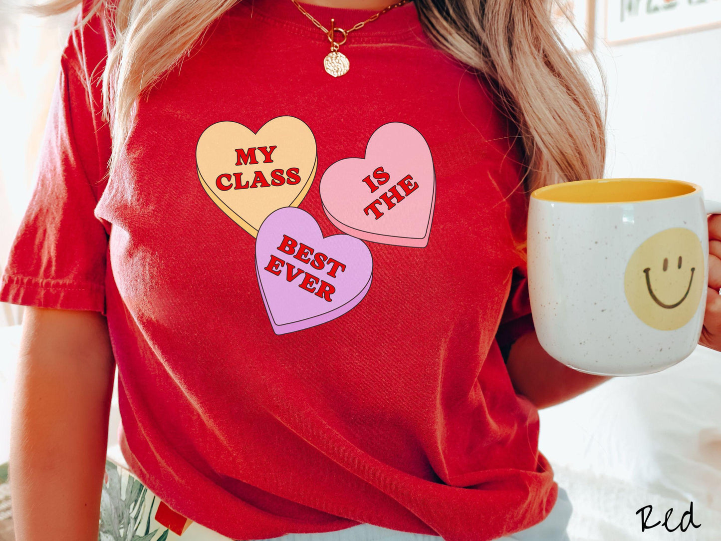 A charming vintage-style Valentine’s Day Comfort Colors t-shirt featuring three vibrant conversation hearts in yellow, red, and purple, this design displays the text “My class is the best ever” spread across the hearts.