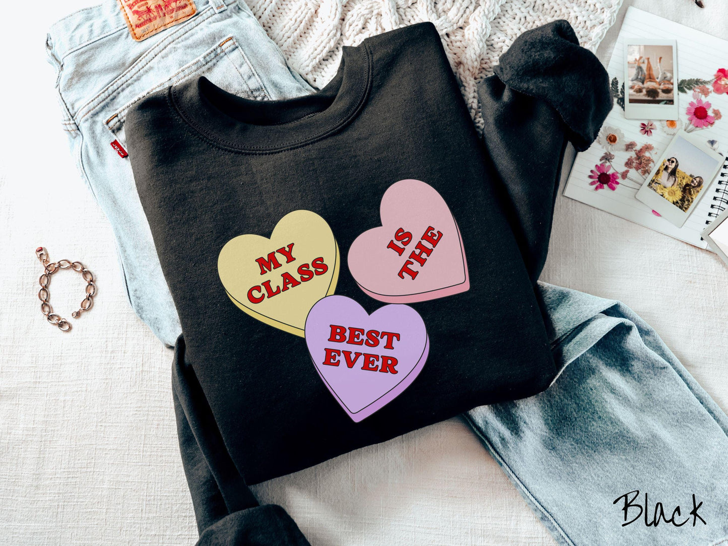 A charming vintage-style Valentine’s Day Gildan sweatshirt featuring three vibrant conversation hearts in yellow, red, and purple, this design displays the text “My class is the best ever” spread across the hearts.