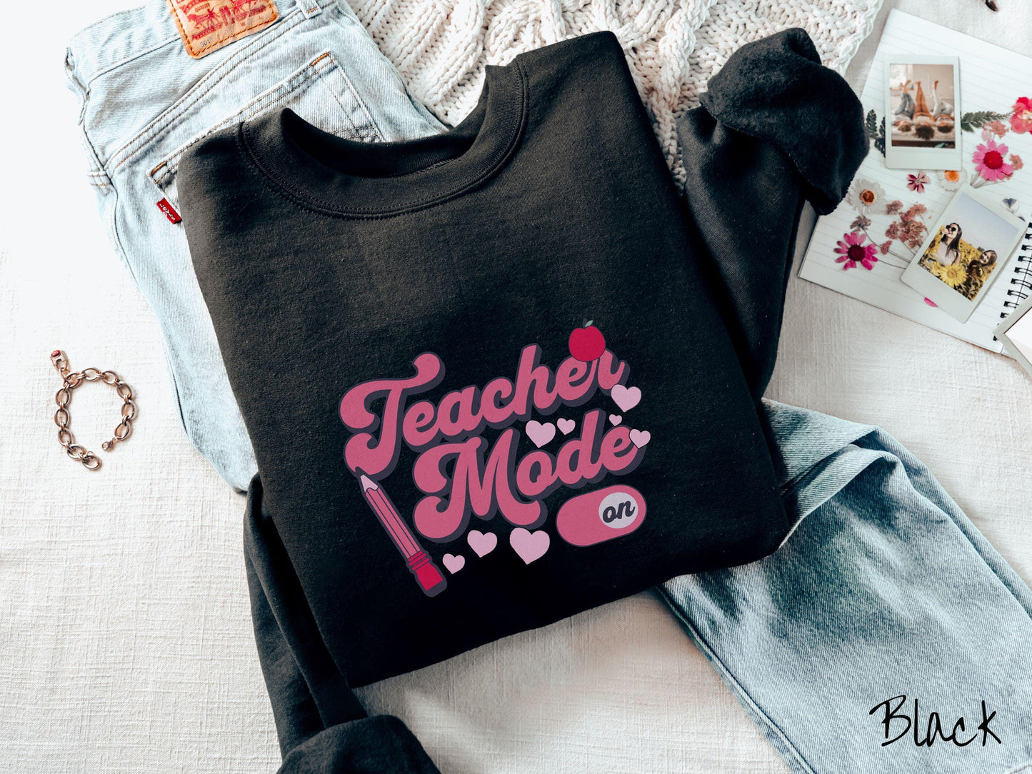 A vintage Gildan sweathirt featuring the phrase “Teacher Mode” in playful pink font, an “On” button toggled to the “On” position, and with charming details like a red pencil, a red apple, and pink hearts sprinkled throughout.