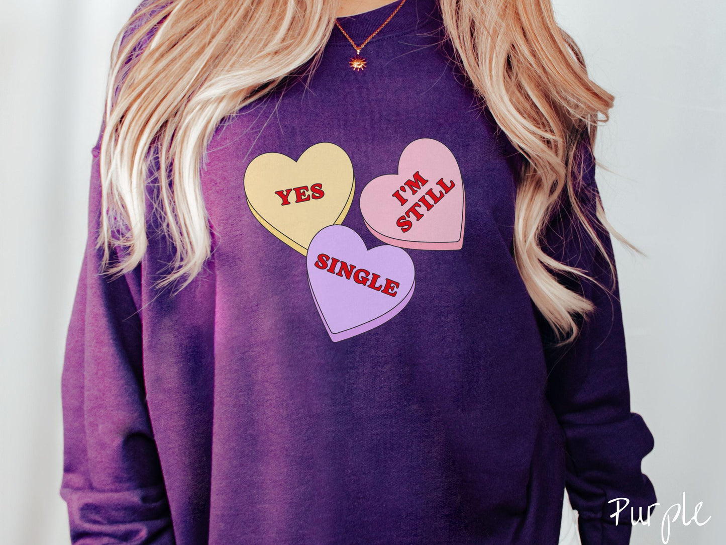 Make a bold statement this Valentine’s Day with this vintage Gildan sweatshirt featuring three vibrant conversation hearts in yellow, red, and purple, the design showcasing the cheeky phrase “Yes, I’m Still Single” spread across the hearts.