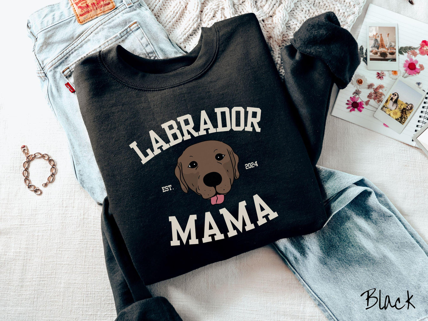 A vintage Gildan sweatshirt featuring bold block lettering that reads 'Labrador Mama.' At the center of the design, a playful chocolate Labrador with its tongue out steals the spotlight, framed by the stylish text 'EST. 2024.'