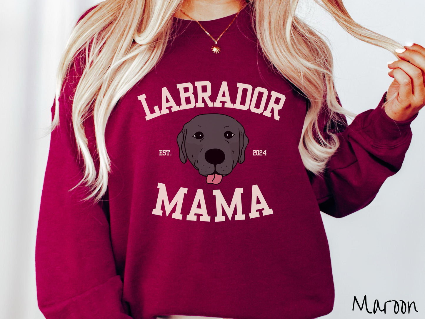 A vintage Gildan sweatshirt featuring bold block lettering that reads 'Labrador Mama.' At the center of the design, a playful black Labrador with its tongue out steals the spotlight, framed by the stylish text 'EST. 2024.'