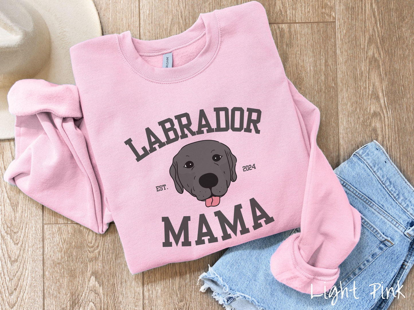 A vintage Gildan sweatshirt featuring bold block lettering that reads 'Labrador Mama.' At the center of the design, a playful black Labrador with its tongue out steals the spotlight, framed by the stylish text 'EST. 2024.'