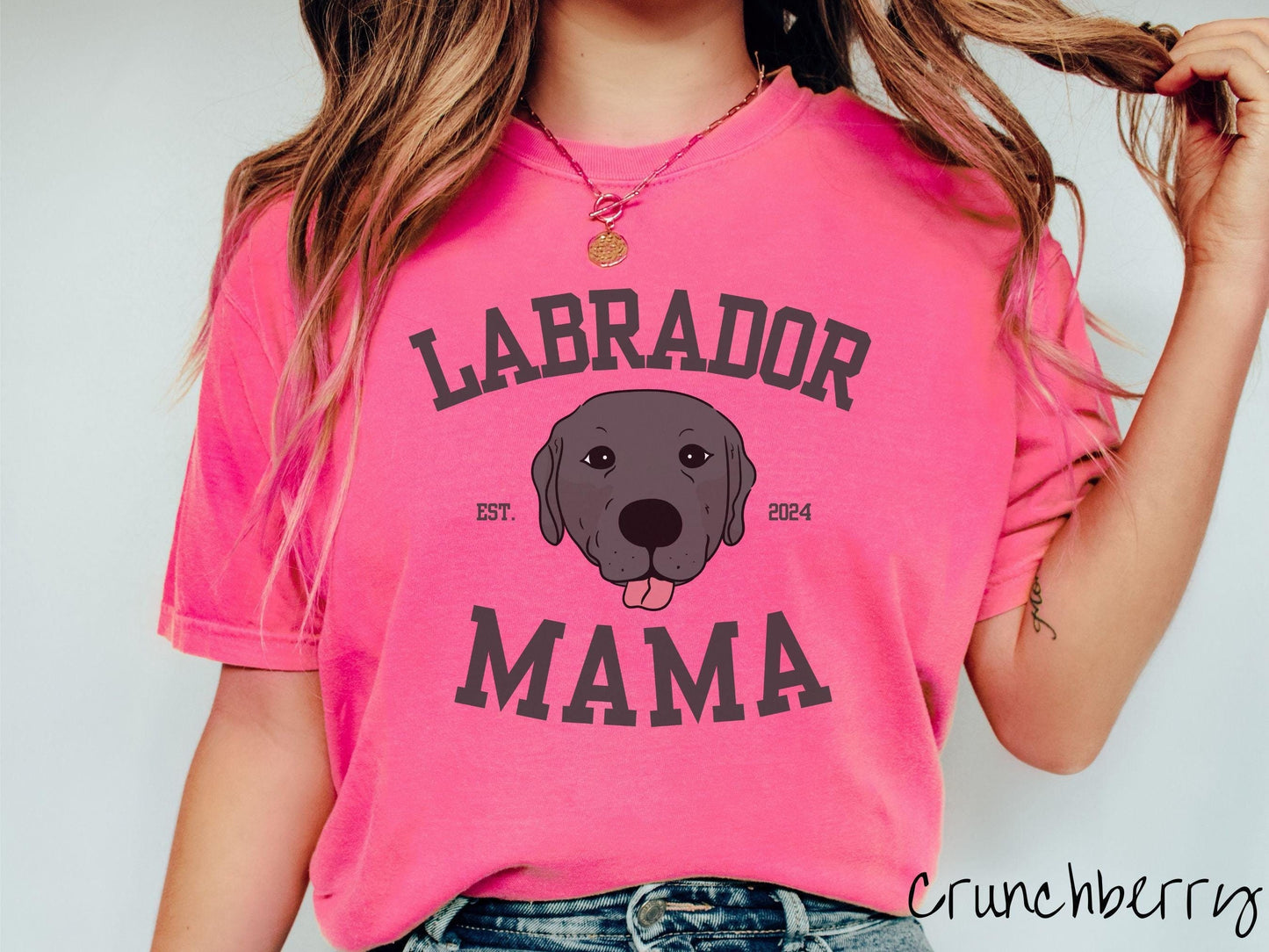 A vintage Comfort Colors t-shirt featuring bold block lettering that reads 'Labrador Mama.' At the center of the design, a playful black Labrador with its tongue out steals the spotlight, framed by the stylish text 'EST. 2024.'