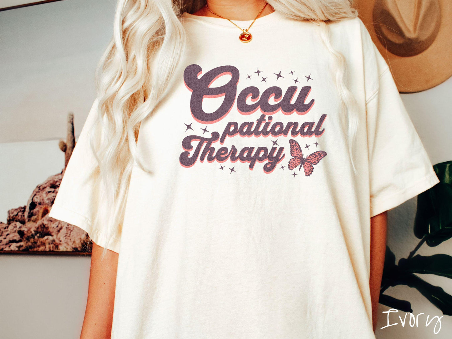 A vintage, ivory colored Comfort Colors t-shirt featuring the words Occupational Therapy across the front, this unique design showcases a stunning pink and dark purple butterfly surrounded by delicate twinkling stars.