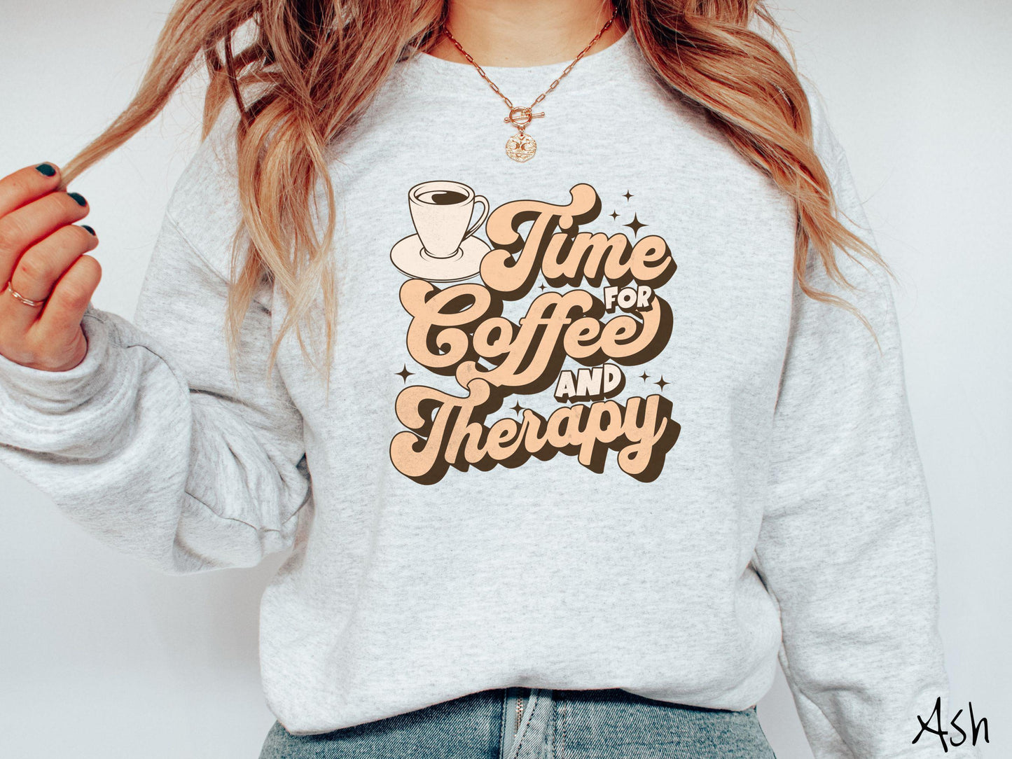 A vintage, ash colored Gildan sweatshirt featuring the text Time for Coffee and Therapy with a cup of coffee and stars in the background, giving off a cozy and comforting vibe.