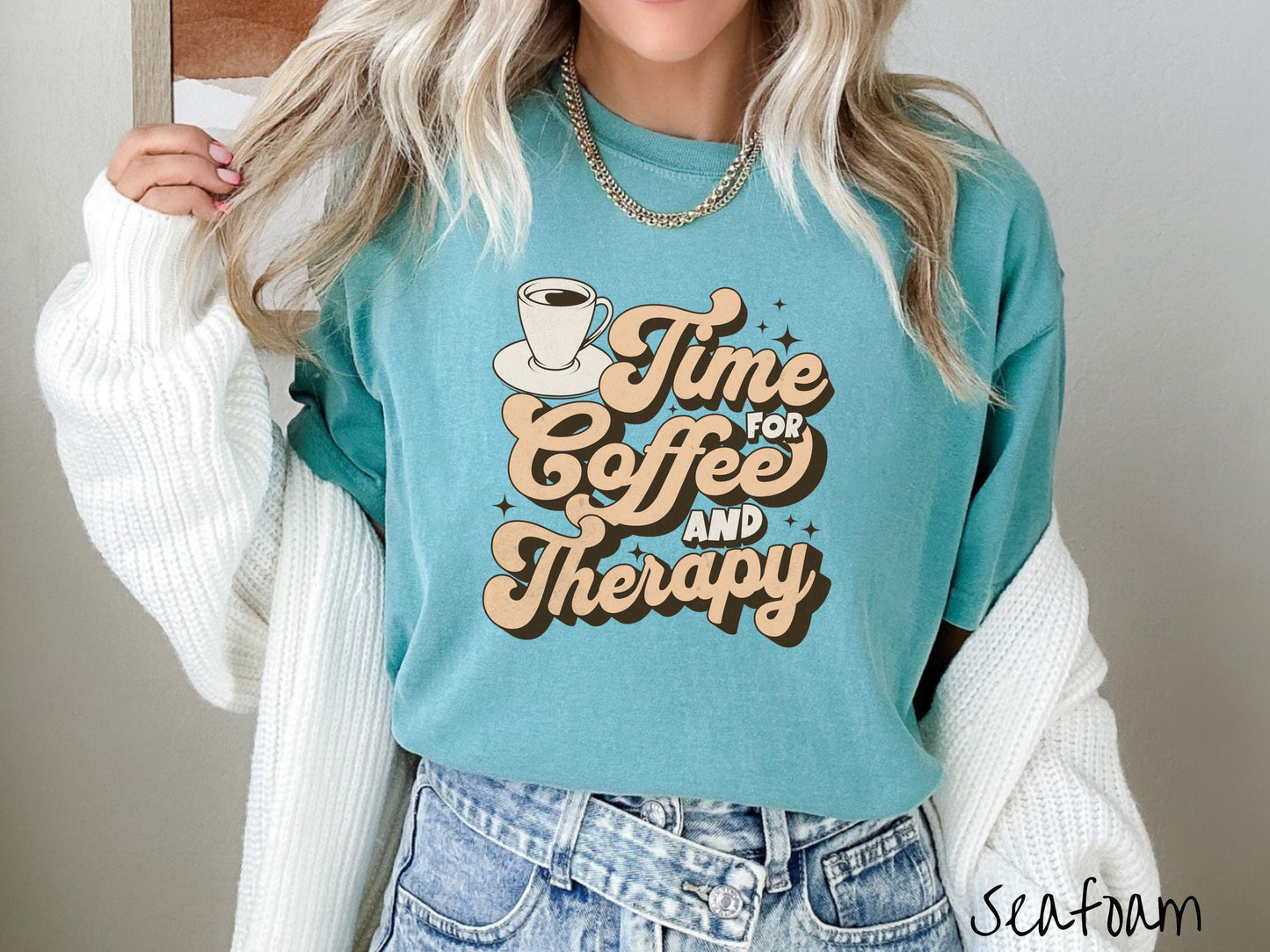 A vintage, seafoam colored Comfort Colors t-shirt featuring the text Time for Coffee and Therapy with a cup of coffee and stars in the background, giving off a cozy and comforting vibe.