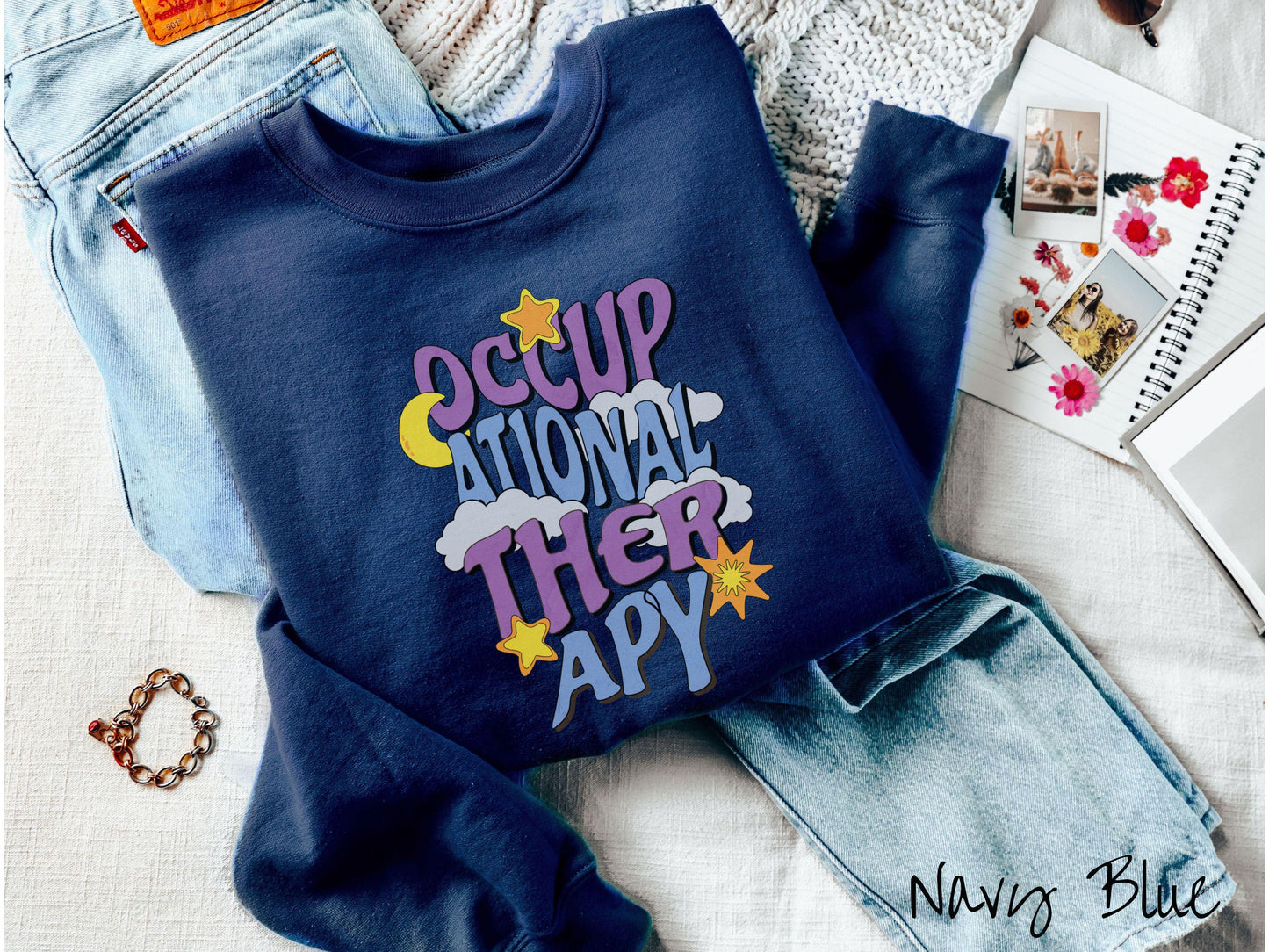 A vintage, navy blue colored Gildan sweatshirt with the text Occupational Therapy vertically with clouds, the yellow moon, and bright yellow and orange stars mixed in.