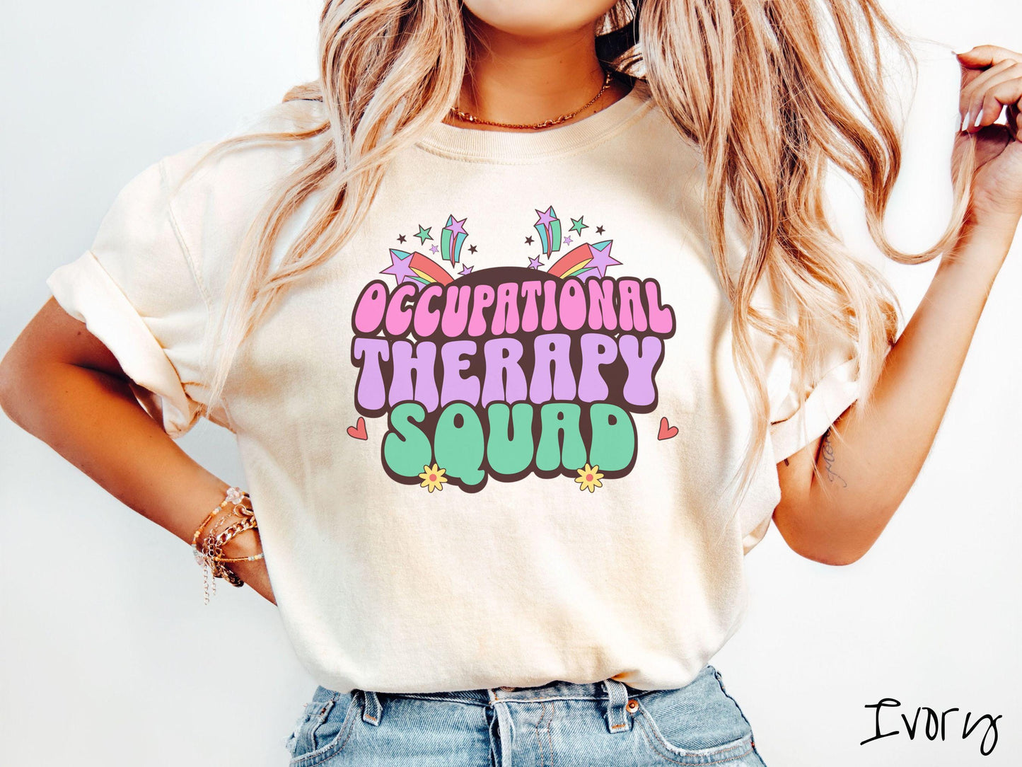 A vintage, ivory colored Comfort Colors T-shirt with the text Occupational Therapy Squad in colorful font with red hearts, sunflowers, and shooting stars mixed in.