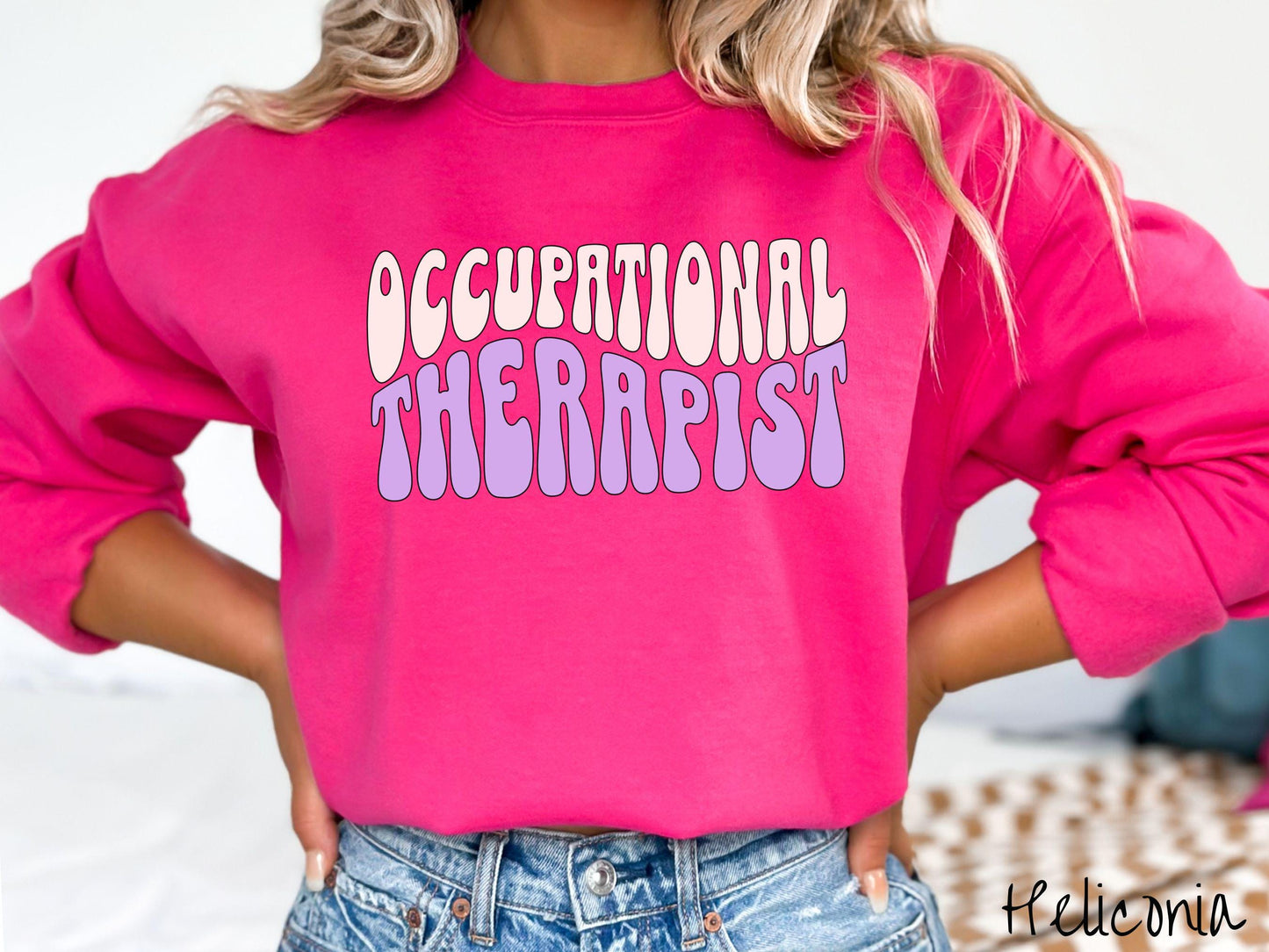 A vintage, heliconia colored Gildan sweatshirt featuring the text Occupational Therapist in fun wavy font. This sweater is perfect for occupational therapists looking to add a touch of personality to their casual or semi-formal outfits.