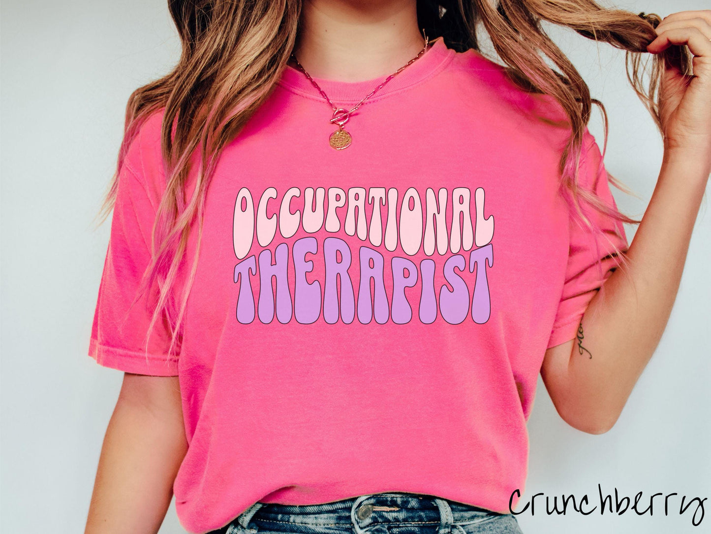 A vintage, crunchberry colored Comfort Colors t-shirt featuring the text Occupational Therapist in fun wavy font. This sweater is perfect for occupational therapists looking to add a touch of personality to their casual or semi-formal outfits.
