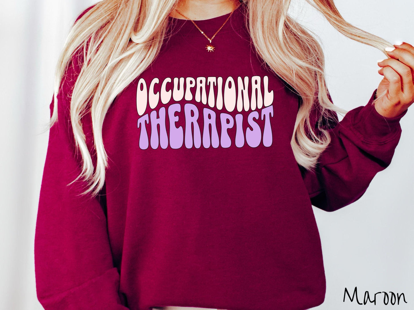 A vintage, maroon colored Gildan sweatshirt featuring the text Occupational Therapist in fun wavy font. This sweater is perfect for occupational therapists looking to add a touch of personality to their casual or semi-formal outfits.