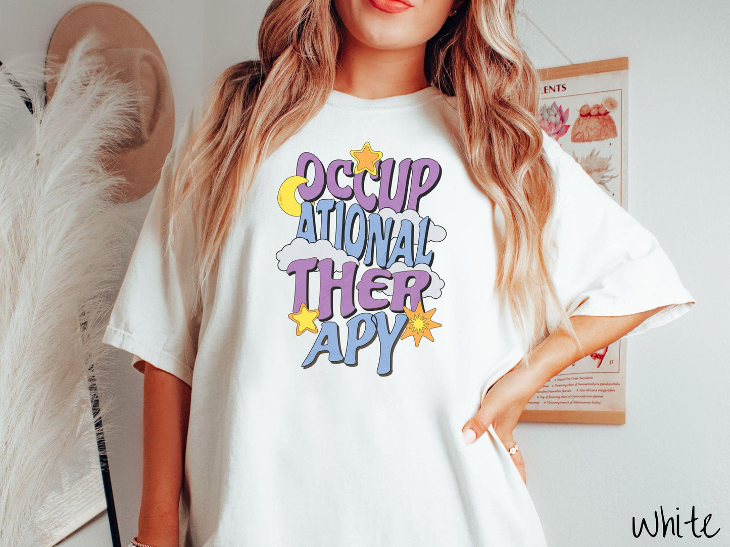 A vintage, white colored Comfort Colors t-shirt with the text Occupational Therapy vertically with clouds, the yellow moon, and bright yellow and orange stars mixed in.