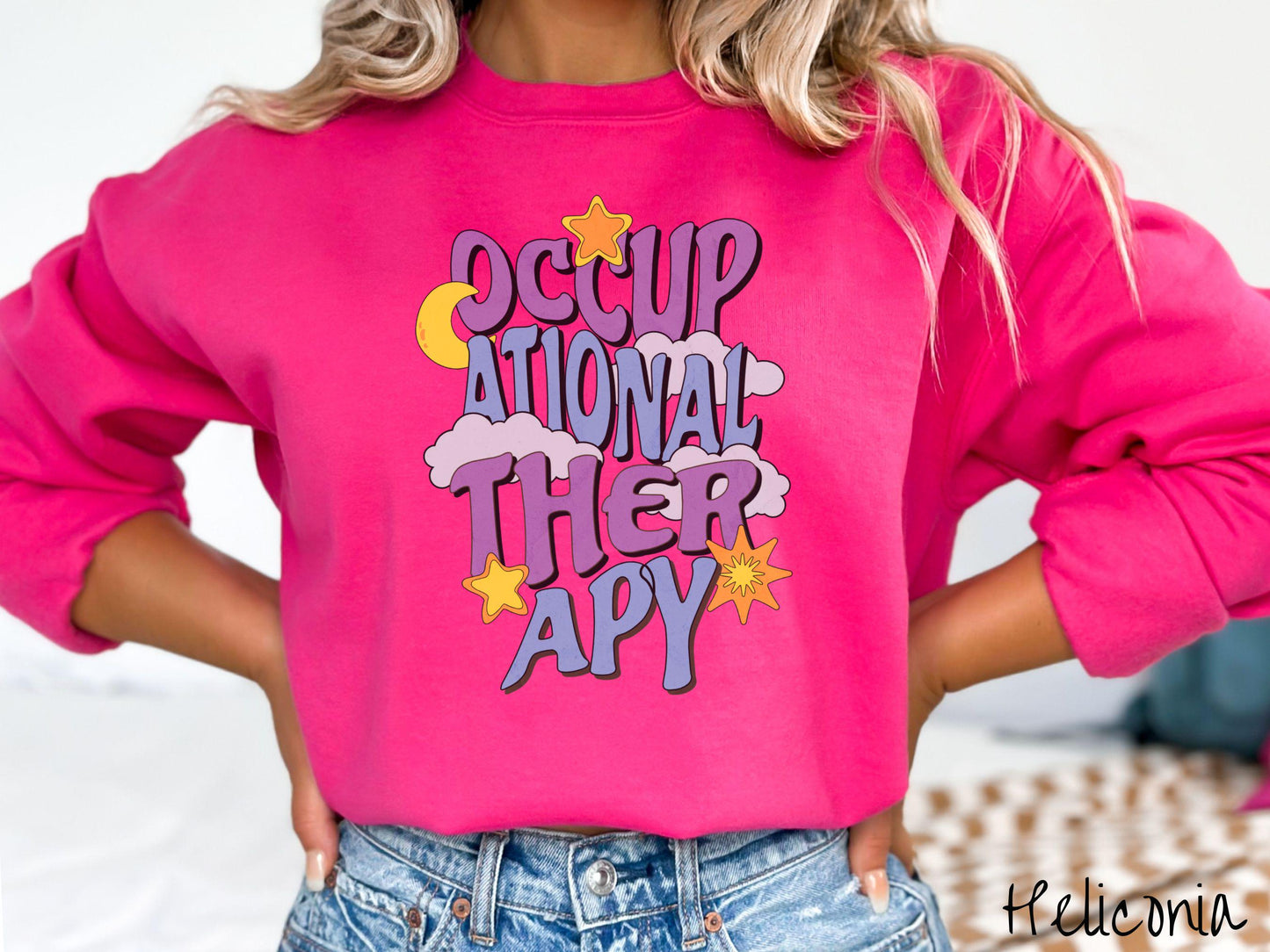 A vintage, heliconia colored Gildan sweatshirt with the text Occupational Therapy vertically with clouds, the yellow moon, and bright yellow and orange stars mixed in.