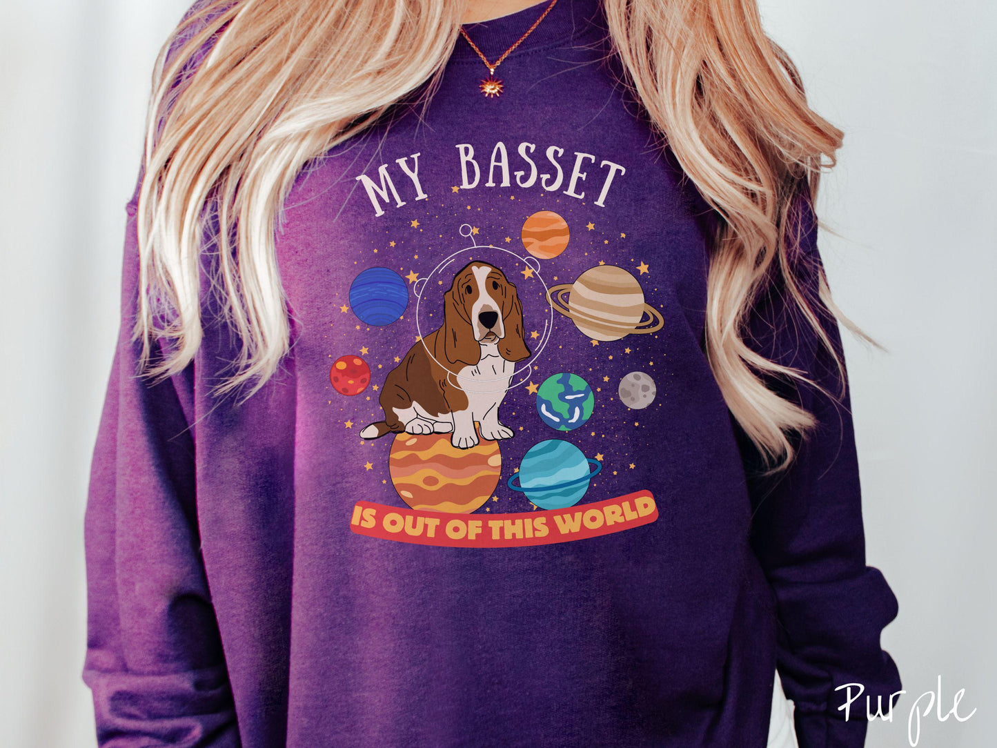 A vintage Gildan sweatshirt featuring the playful text 'My Basset is Out of This World'. The design showcases a basset hound sitting proudly atop Jupiter, surrounded by a vibrant solar system filled with colorful planets and twinkling stars.