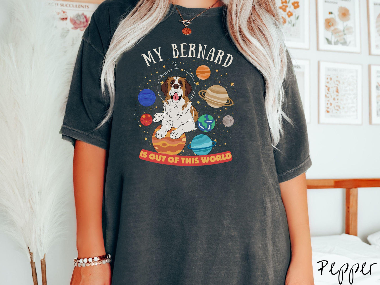 A vintage Comfort Colors t-shirt featuring the text 'My Bernard is Out of This World'. The design showcases an adorable St. Bernard sitting proudly atop Jupiter, surrounded by a vibrant solar system filled with colorful planets and twinkling stars.