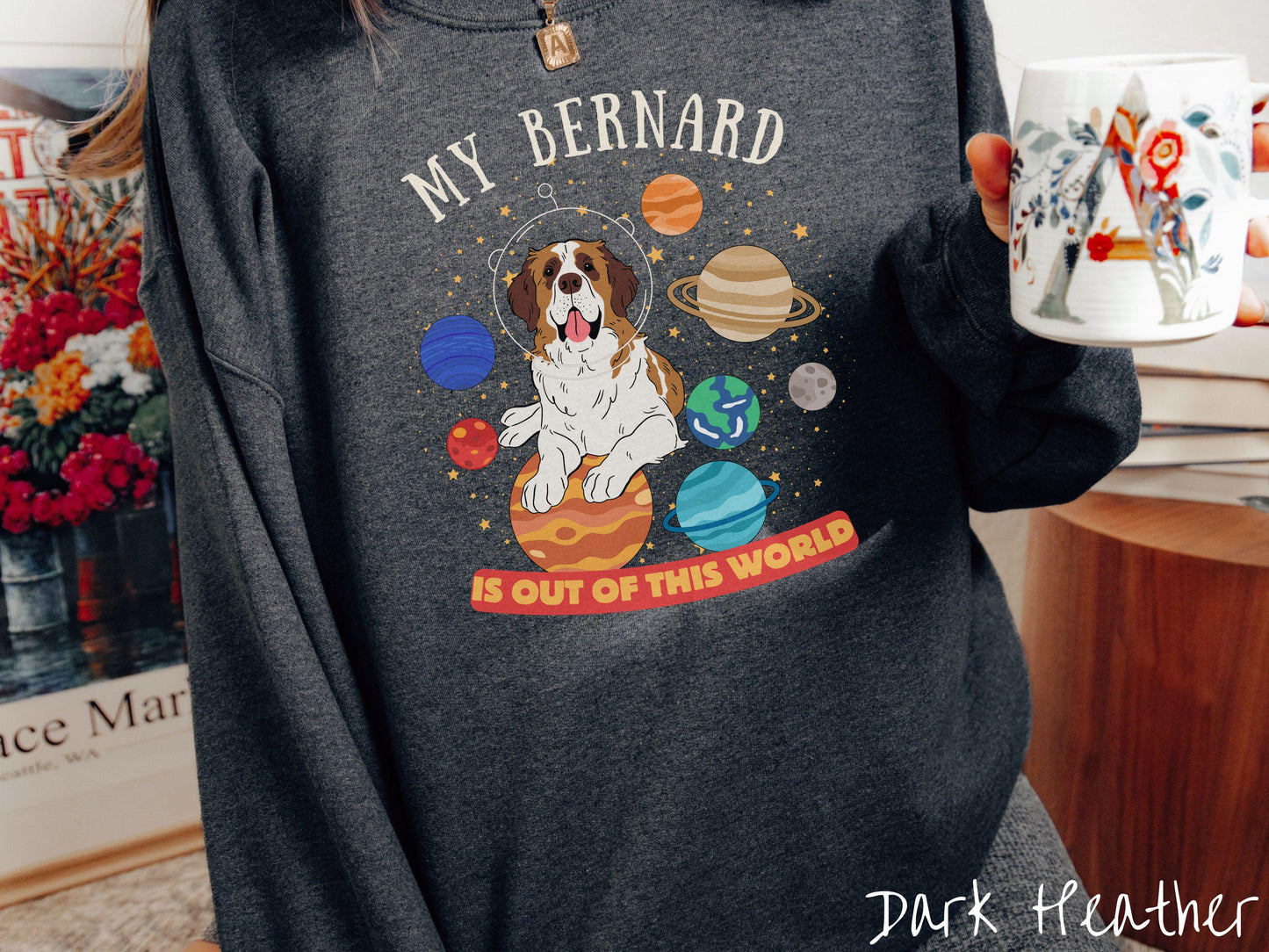 A vintage Gildan sweatshirt featuring the text 'My Bernard is Out of This World'. The design showcases an adorable St. Bernard sitting proudly atop Jupiter, surrounded by a vibrant solar system filled with colorful planets and twinkling stars.