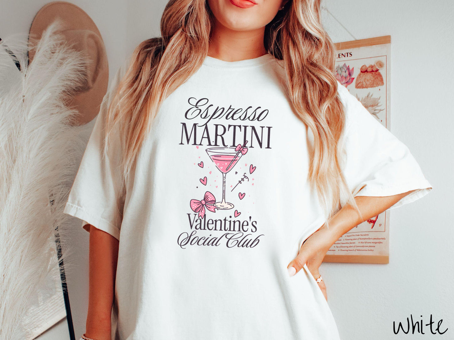 A stylish Comfort Colors T-shirt featuring the phrase "Espresso Martini" above a martini glass filled with pink martini a pink bow-topped toothpick. The words "Valentine's Social Club" appear below, with pink bows and hearts throughout the design.