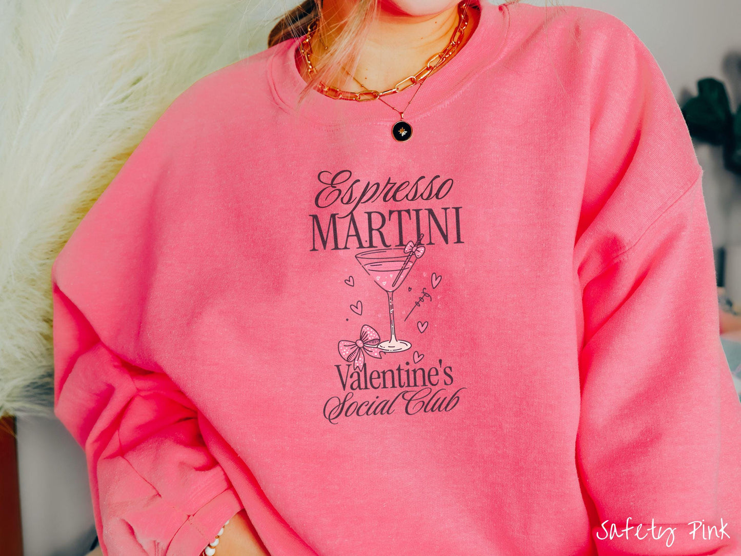 A stylish Gildan sweatshirt featuring the phrase "Espresso Martini" above a martini glass filled with pink martini and a pink bow-topped toothpick. The words "Valentine's Social Club" appear below with pink bows and hearts throughout the design.