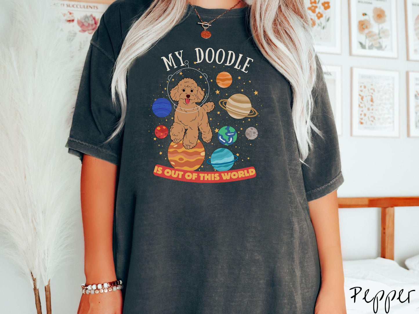A vintage Comfort Colors t-shirt featuring the text My Doodle is Out of This World. The design showcases a Doodle sitting proudly atop Jupiter, surrounded by a vibrant solar system filled with colorful planets and twinkling stars.