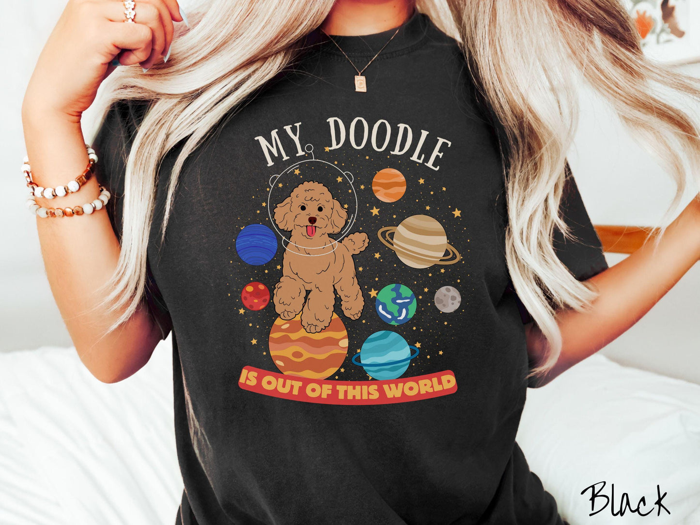 A vintage Comfort Colors t-shirt featuring the text My Doodle is Out of This World. The design showcases a Doodle sitting proudly atop Jupiter, surrounded by a vibrant solar system filled with colorful planets and twinkling stars.