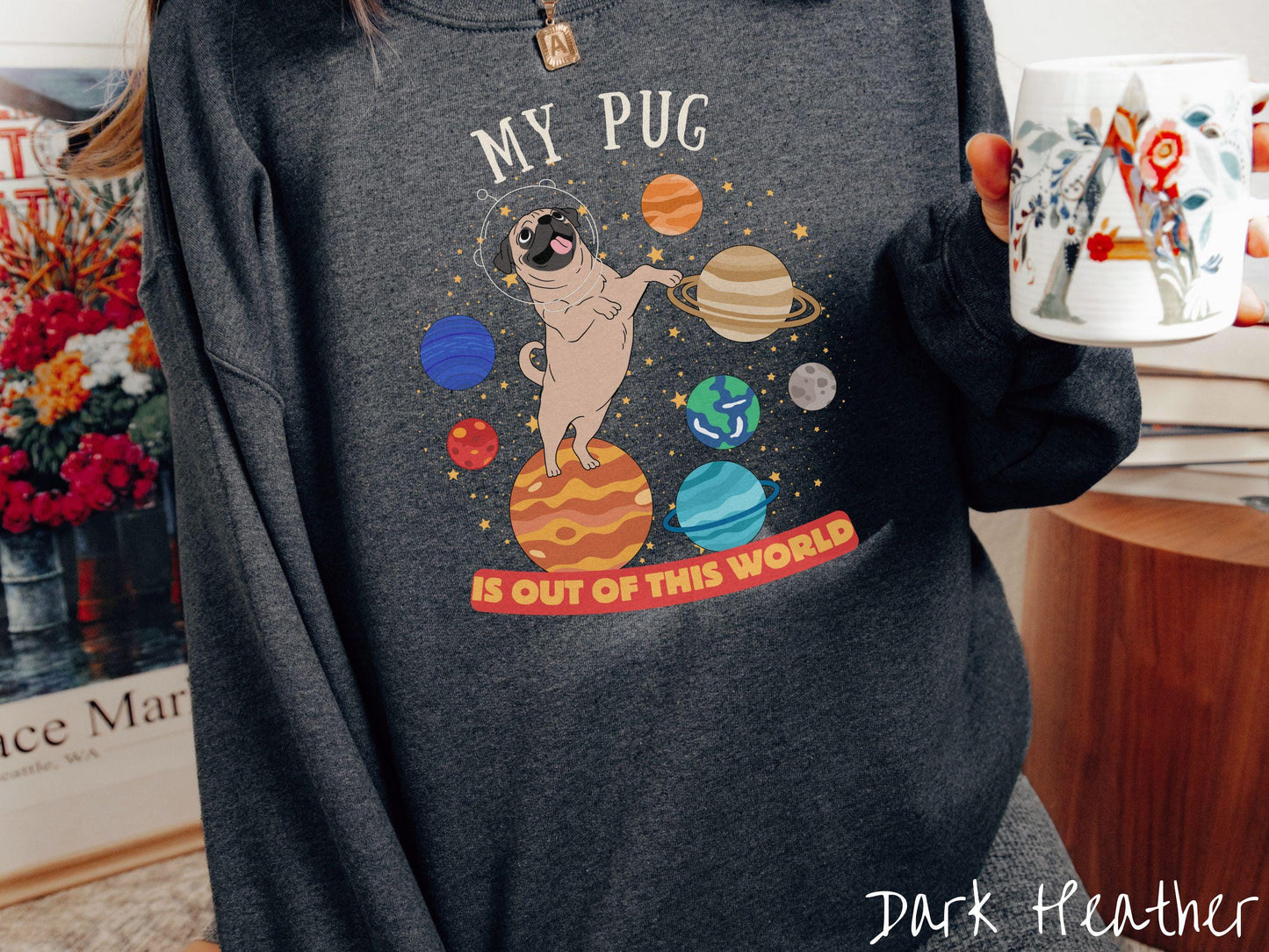 A vintage Gildan sweatshirt featuring the text My Pug is Out of This World. The design showcases an adorable Pug sitting proudly atop Jupiter, surrounded by a vibrant solar system filled with colorful planets and twinkling stars.