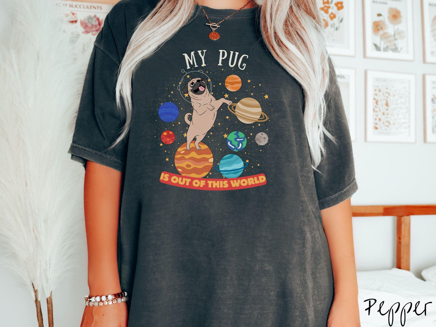 A vintage Comfort Colors t-shirt featuring the text My Pug is Out of This World. The design showcases an adorable Pug sitting proudly atop Jupiter, surrounded by a vibrant solar system filled with colorful planets and twinkling stars.