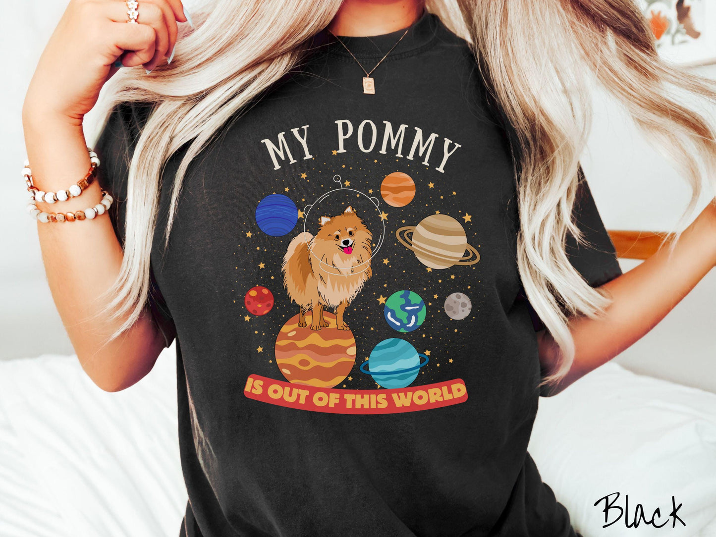 A vintage Comfort Colors t-shirt featuring the text My Pomeranian is Out of This World. The design showcases an adorable Pomeranian sitting proudly atop Jupiter, surrounded by a vibrant solar system filled with colorful planets and twinkling stars.