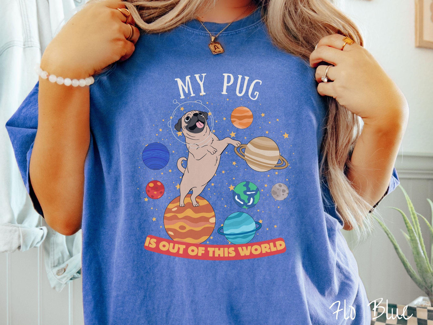 A vintage Comfort Colors t-shirt featuring the text My Pug is Out of This World. The design showcases an adorable Pug sitting proudly atop Jupiter, surrounded by a vibrant solar system filled with colorful planets and twinkling stars.