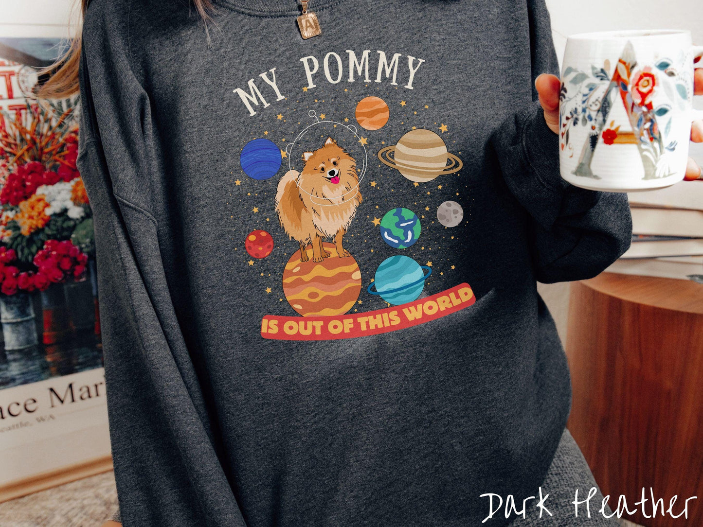 A vintage Gildan sweatshirt featuring the text My Pomeranian is Out of This World. The design showcases a German Shepherd sitting proudly atop Jupiter, surrounded by a vibrant solar system filled with colorful planets and twinkling stars.
