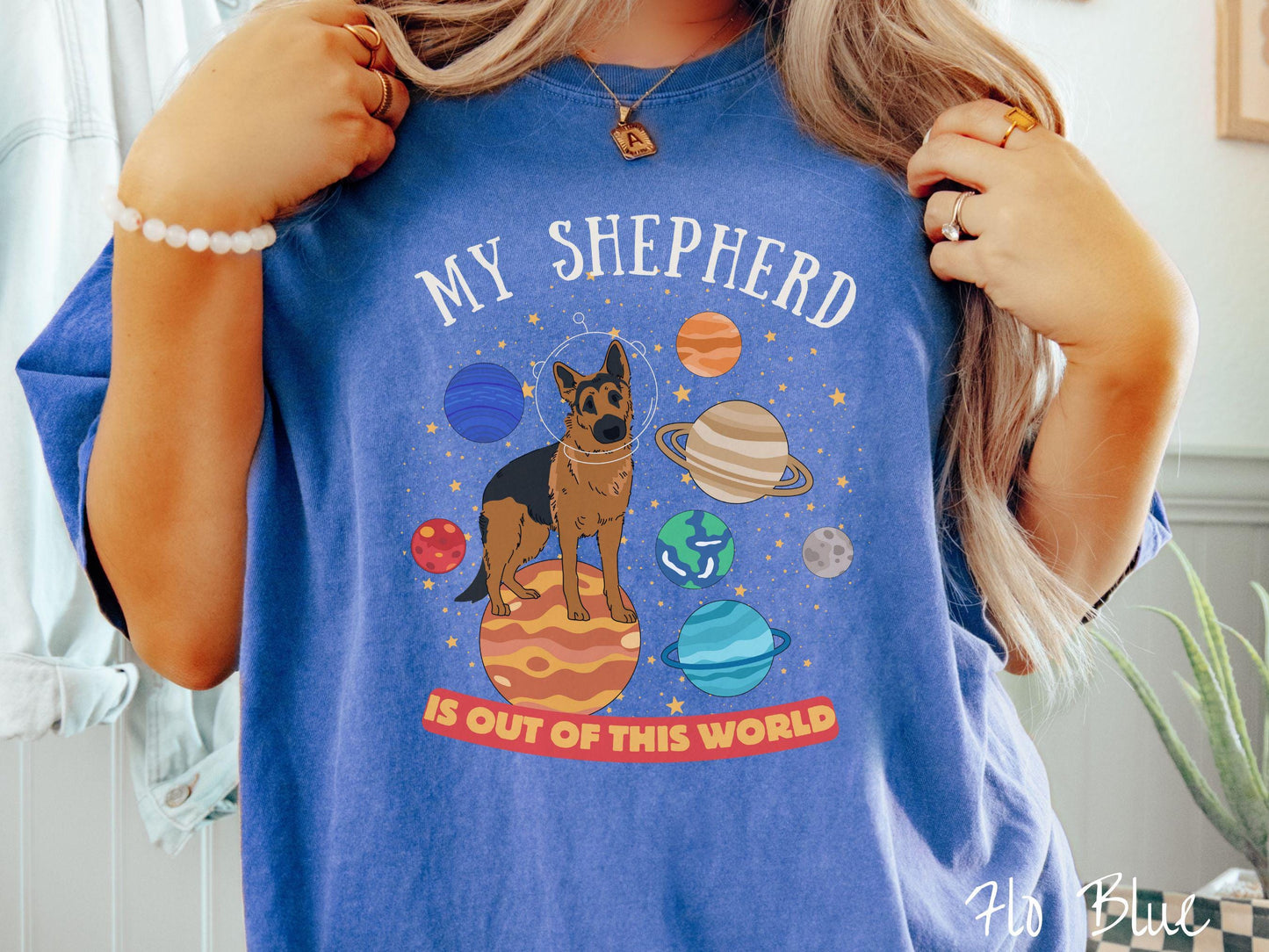 A vintage Comfort Colors t-shirt featuring the text My Shepherd is Out of This World. The design showcases a German Shepherd sitting proudly atop Jupiter, surrounded by a vibrant solar system filled with colorful planets and twinkling stars.