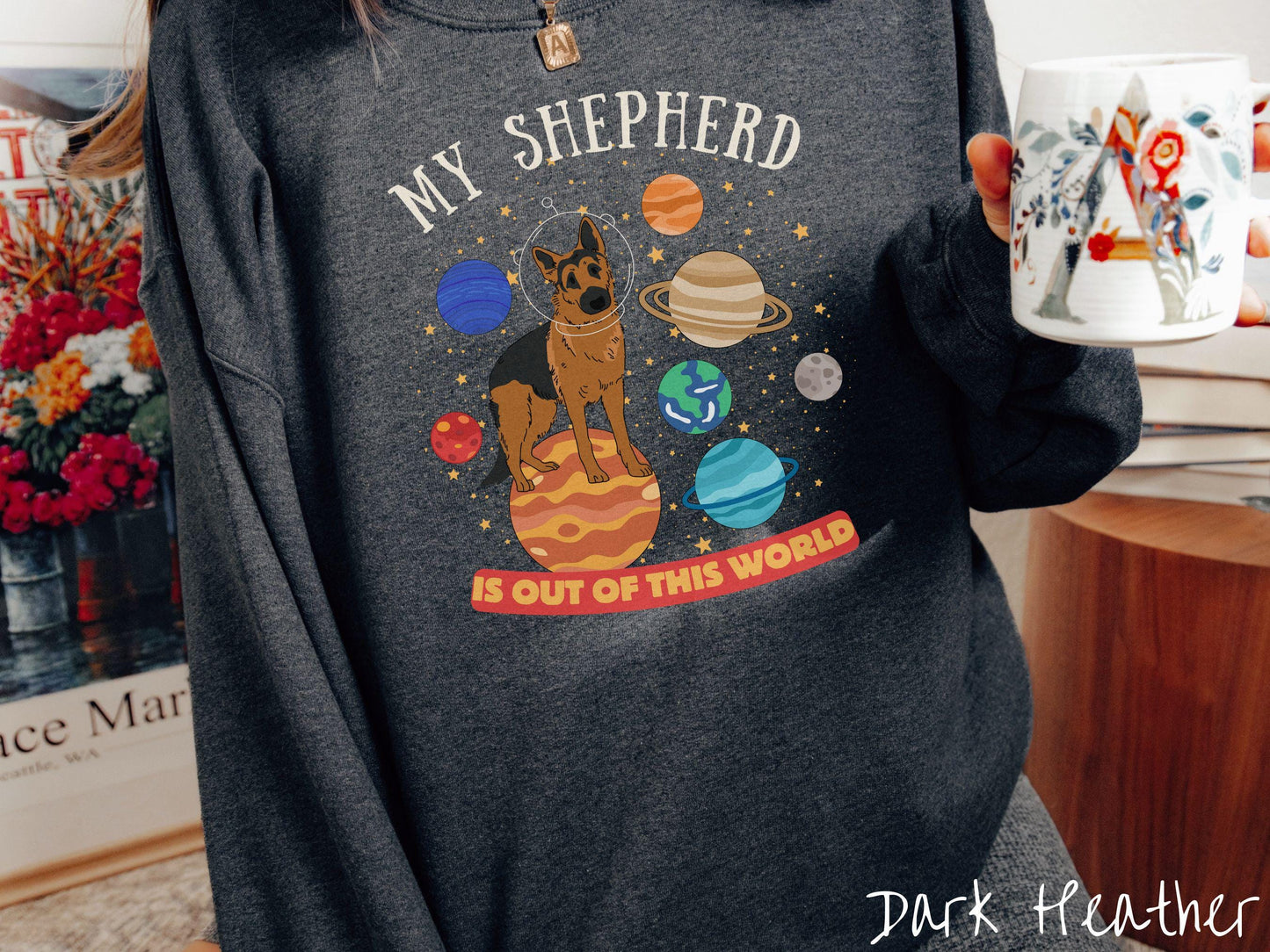 A vintage Gildan sweatshirt featuring the text My Shepherd is Out of This World. The design showcases a German Shepherd sitting proudly atop Jupiter, surrounded by a vibrant solar system filled with colorful planets and twinkling stars.
