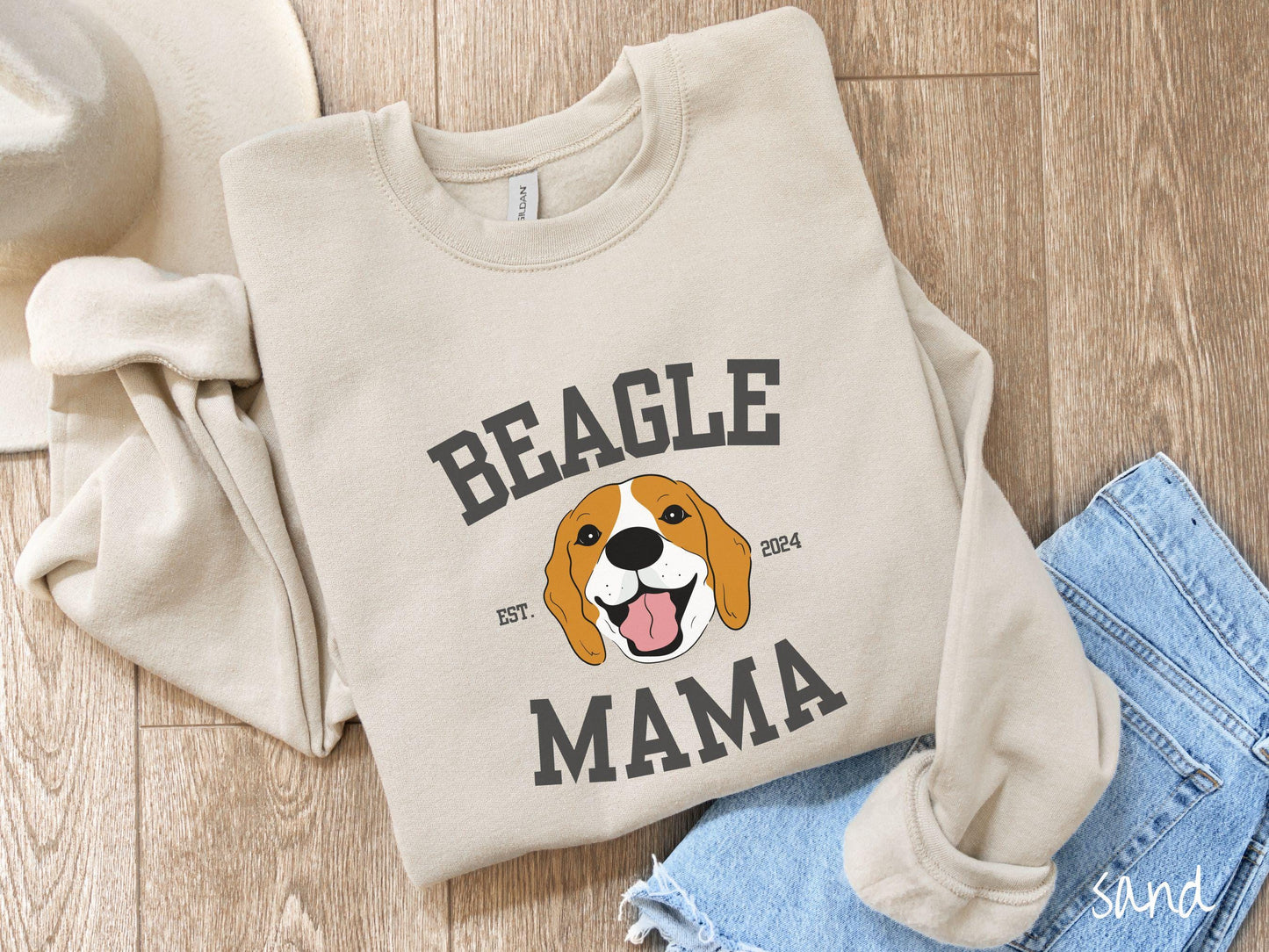 A vintage Gildan sweatshirt for every proud Beagle Mama! The design features the words Beagle Mama in a university-style font, framing an orange, black, and brown beagle. The playful touch of "EST. 2024" adds a personal charm to the design.