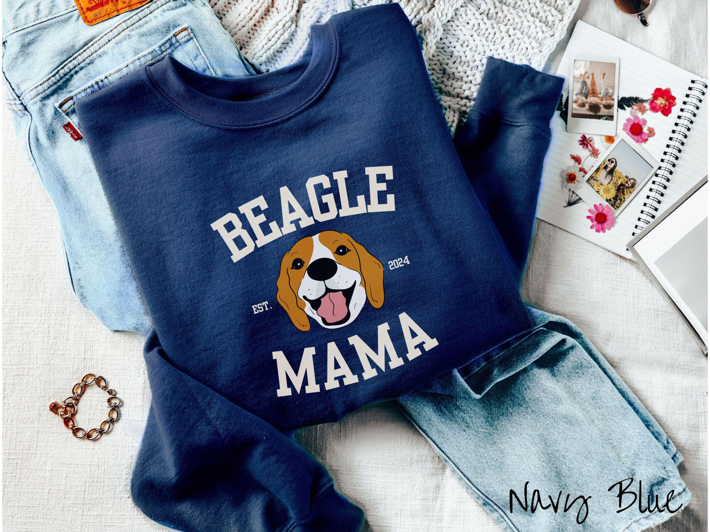 A vintage Gildan sweatshirt for every proud Beagle Mama! The design features the words Beagle Mama in a university-style font, framing an orange, black, and brown beagle. The playful touch of "EST. 2024" adds a personal charm to the design.