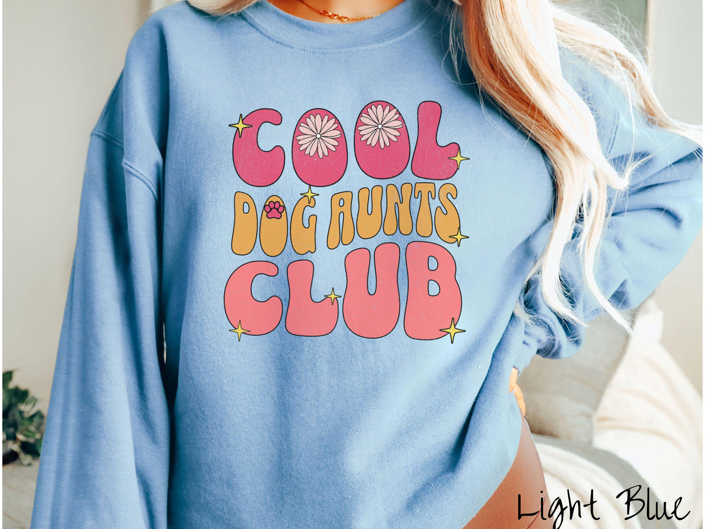A vintage Gildan sweatshirt featuring the text "Cool Dog Aunts Club" in bold red, yellow, and orange fonts with flower petals nestled in the "O" of COOL, a cute red paw print in the "O" of DOG, and sparkling yellow stars throughout.