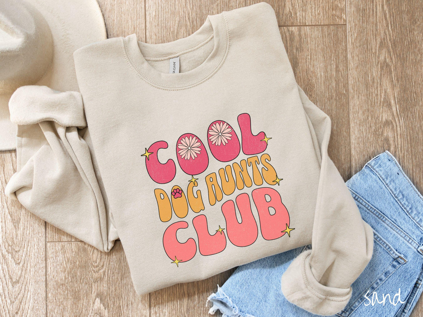 A vintage Gildan sweatshirt featuring the text "Cool Dog Aunts Club" in bold red, yellow, and orange fonts with flower petals nestled in the "O" of COOL, a cute red paw print in the "O" of DOG, and sparkling yellow stars throughout.